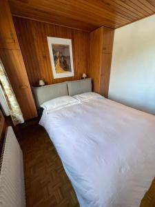 a large white bed in a room with wooden walls at Lovely Apt Chalet Courchevel 1650 in Courchevel