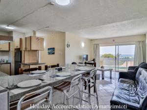 a kitchen and living room with a table and chairs at Holiday Accommodation Amanzimtoti in Amanzimtoti