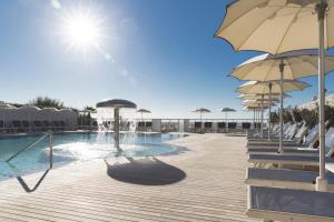 a swimming pool with umbrellas and chairs next to a swimming pool at Hotel Cambridge in Lido di Jesolo