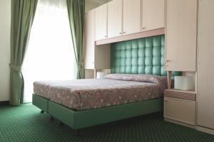 a bedroom with a bed with a green headboard at Hotel Cambridge in Lido di Jesolo
