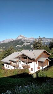 una gran casa en una colina con montañas en el fondo en Crest Voland, Le Cernix studio de standing rénové en Cohennoz
