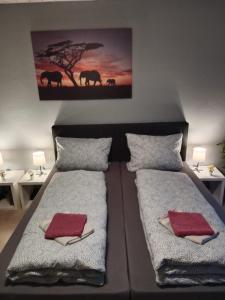 een slaapkamer met twee bedden met handdoeken en een foto van olifanten bij Stadtnah an der Förde 65 U in Flensburg