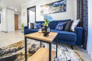 ein blaues Sofa im Wohnzimmer mit einem Tisch in der Unterkunft Sun Towers - Apartamenty Bryza - Apartamenty z parkingiem in Świnoujście