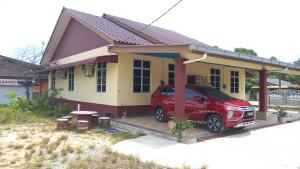 um carro vermelho estacionado em frente a uma casa em Mufeed Homestay em Kampong Wakaf Tengah