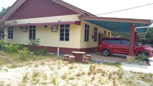 una furgoneta roja estacionada frente a una casa en Mufeed Homestay, en Kampong Wakaf Tengah