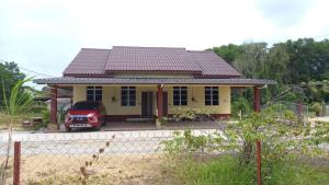 a yellow house with a red car parked in front of it at Mufeed Homestay in Kampong Wakaf Tengah