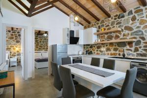 een keuken met een tafel en stoelen en een stenen muur bij Petra Residence in Skala Potamias