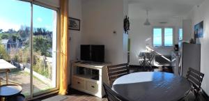sala de estar con mesa, TV y ventana en Mer en Vue - 2 Chambres- 4 Personnes, en Fécamp
