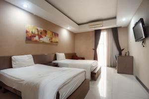 een hotelkamer met 2 bedden en een televisie bij Safwah Bintaro Syariah Mitra RedDoorz in Tangerang