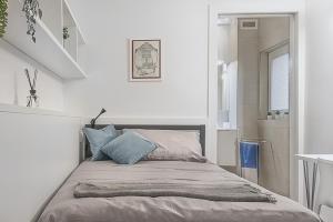 een bed in een witte kamer met blauwe kussens bij Porta Palio Luxury Apartment in Verona