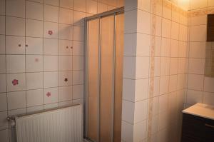 La salle de bains est pourvue d'une douche et de carrelage blanc. dans l'établissement Villa Viola, à Moosburg