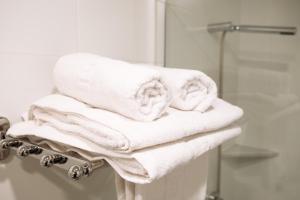 a pile of towels on a towel rack in a bathroom at Apartahotel Golden Alcalá in Alcalá de Henares