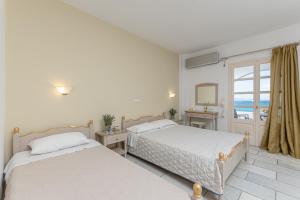 two beds in a white room with a window at Orkos View in Mikri Vigla