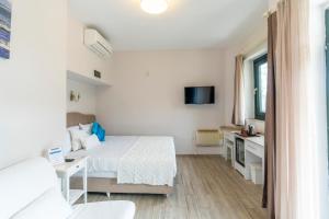 a white bedroom with a bed and a tv at Villa Marine Hotel in Akyaka