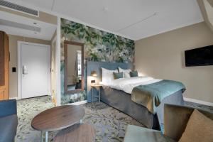 オスロにあるクラリオン コレクションホテル ガーベルスフースのベッドとテーブルが備わるホテルルームです。