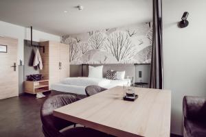 1 dormitorio con 1 cama y 1 mesa con sillas en ADEBAR Stadthotel en Dingolfing