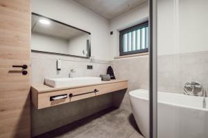 a bathroom with a sink and a tub and a toilet at ADEBAR Stadthotel in Dingolfing