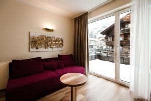 トゥクスにあるAparthotel Dorfplatzl Garniの紫色のソファと大きな窓付きのリビングルーム