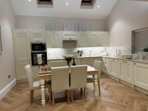 eine Küche mit einem Tisch und Stühlen sowie eine Küche mit weißen Schränken in der Unterkunft Strother's Townhouse in Berwick-Upon-Tweed