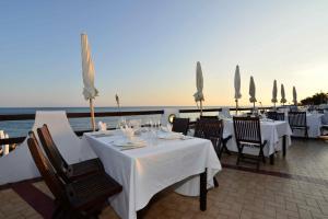 a restaurant with white tables and chairs and the ocean at Hotel Cavalluccio Marino in Santa Marinella