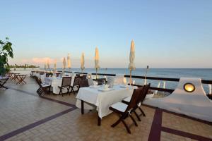 a restaurant with white tables and chairs and the ocean at Hotel Cavalluccio Marino in Santa Marinella