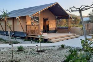 a luxury tent with a porch in a garden at Luxe Safari Lodge Glamping Louloudia in Pitsidia