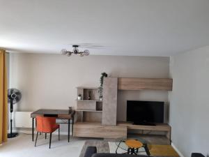 a living room with a television and a table and chairs at LE MONTI appartement proche MEETT, Aéroport Blagnac, Airbus, Golf international de Seilh in Mondonville