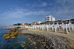 a beach with white umbrellas and a building at Hotel Cavalluccio Marino in Santa Marinella