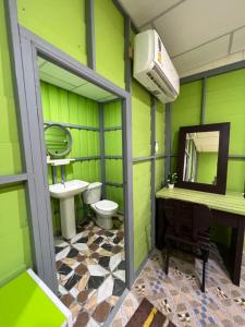 a green bathroom with a toilet and a sink at Baan Tarn Naam in Ban Lam Ru (1)