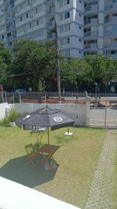 um guarda-chuva preto e uma cadeira na relva em Casarão Hostel & Quartos Privados em Florianópolis