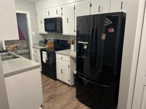 a black refrigerator in a kitchen with white cabinets at Large Bedroom With 2 Queen Bed in Charlotte