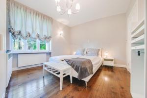 a white bedroom with a bed and a window at Apartamenty Sun & Snow Dębowa in Sopot