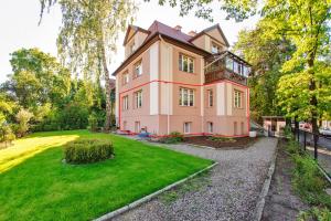 a large pink house with a grass yard at Apartamenty Sun & Snow Dębowa in Sopot