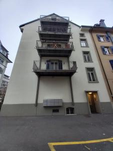 a tall white building with balconies on the side of it at HITrental Station Apartments in Lucerne