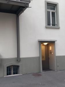 ein weißes Gebäude mit einer Tür und einem Fenster in der Unterkunft HITrental Station Apartments in Luzern