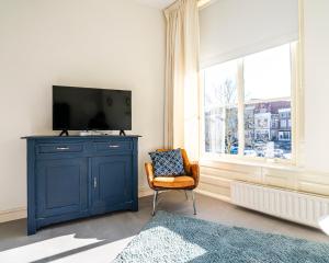een woonkamer met een blauwe kast en een televisie bij Nr 19 Bed and Bubbels in Middelburg