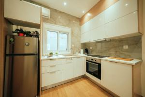 uma cozinha com armários brancos e um frigorífico de aço inoxidável em The Sandbox em Atenas