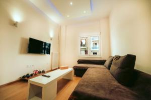 uma sala de estar com um sofá e uma televisão de ecrã plano em The Sandbox em Atenas