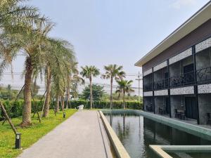 een gebouw met een zwembad en palmbomen bij วิวไม้ รีสอร์ท in Ban Khao Sai