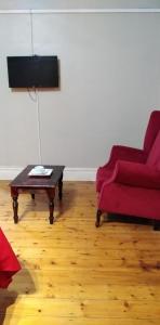 Sala de estar con sofá rojo y mesa de centro en Fabulous guest house en Pietermaritzburg