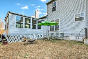 a patio with a table and a green umbrella at Alexandria Area Vacation Rental with Backyard in Accokeek