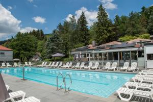 a swimming pool with white chairs and a building at Domaine Long Pre in Stavelot