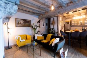 a living room with a black couch and yellow chairs at La Tour aux Grains chambres autonomes in Romorantin