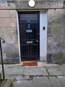 a black door with a number on it in a building at The Wee Room -Stay Where All St Andrews is on the Doorstep! in Fife