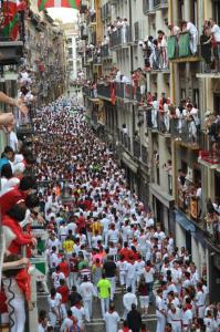 una grande folla di persone che camminano per una strada di città di Casa del Encierro - Estafeta a Pamplona