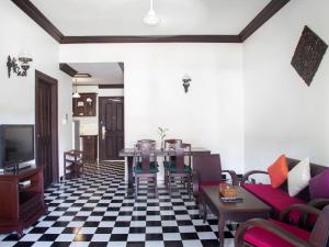 a living room with a table and chairs and a tv at Chateau d'Angkor La Residence in Siem Reap