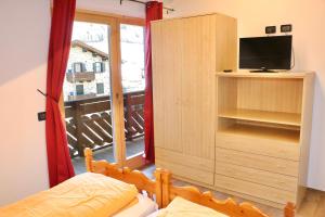 a bedroom with a cabinet with a television and a balcony at Casa Severina in Livigno