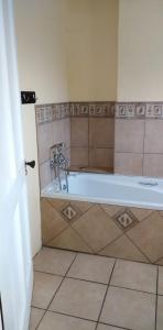 a bathroom with a tub and a tiled floor at Fabulous guest house in Pietermaritzburg