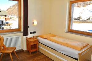 niewielka sypialnia z łóżkiem i oknem w obiekcie Casa Severina w Livigno
