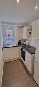 cocina con armarios blancos y encimera negra en Merchantcityflat, en Glasgow